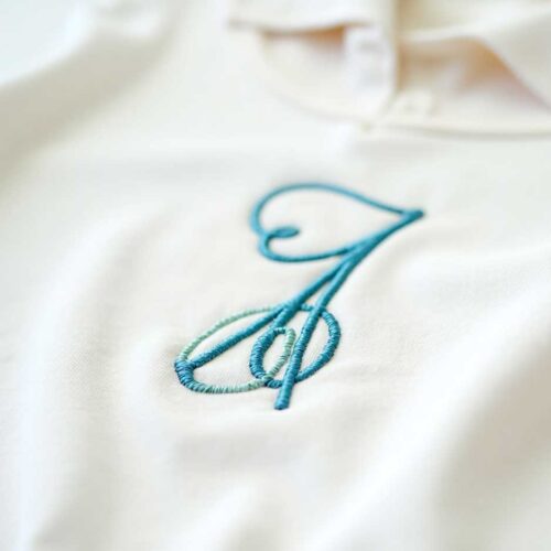 Photo of an initial embroidered in cotton on a pajama or underwear, close app, realistic and very clear
